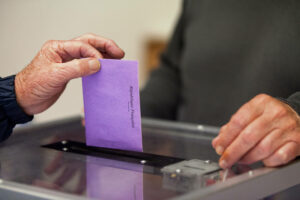 A senior inserting his vote through the slot of the ballot box during the election.